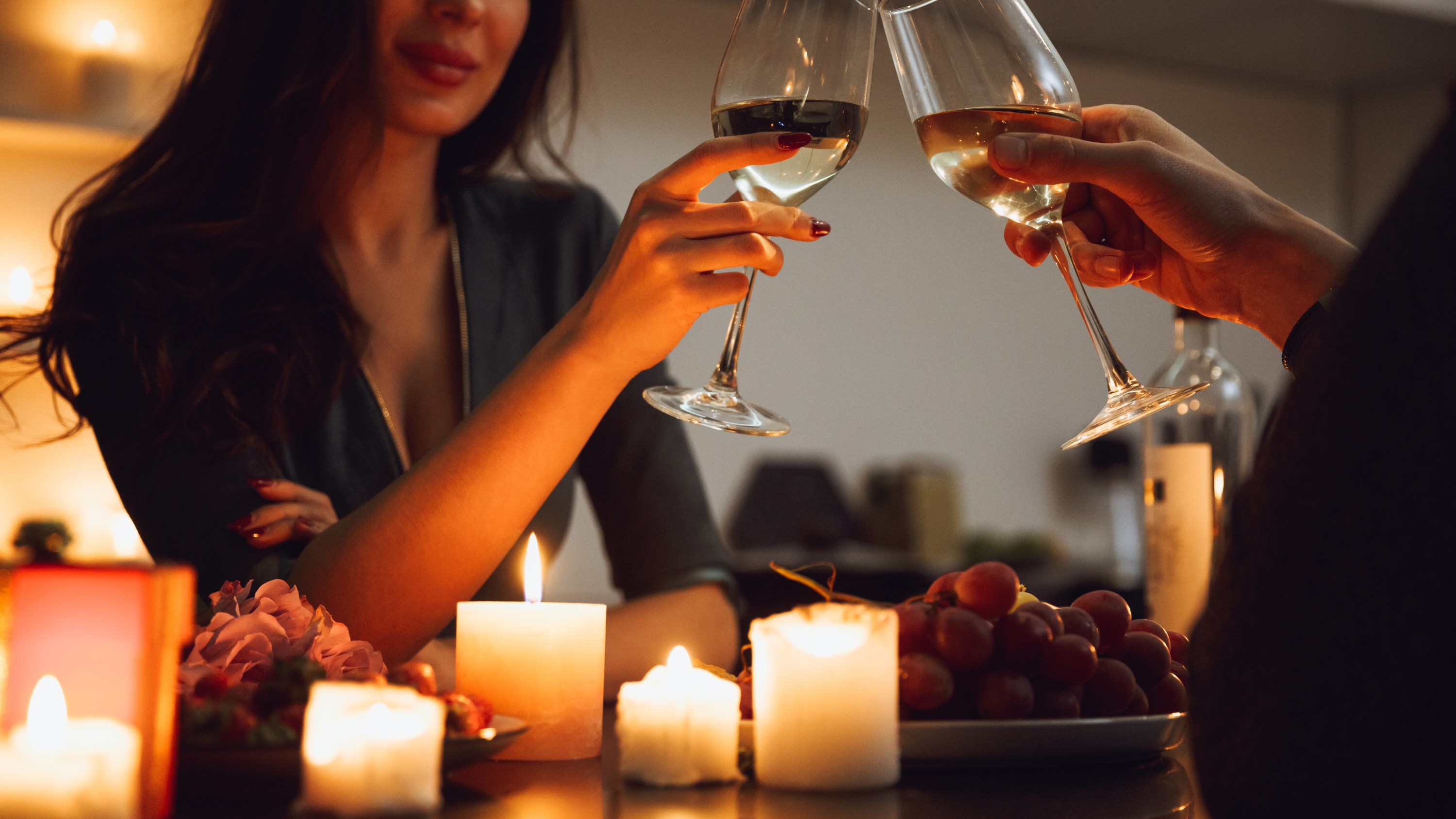 Beautiful passionate couple having a romantic candlelight dinner at home, drinking wine, toasting