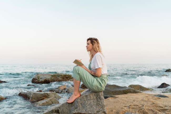 Woman journaling by the ocean