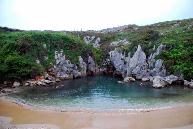 An ocean seeping under rocks and onto the shore of Gulpiyuri Beach, Spain