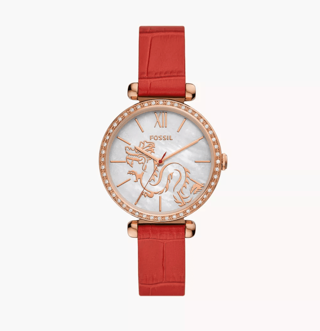 A Fossil watch with a red leather band and a rose gold face with a dragon on it