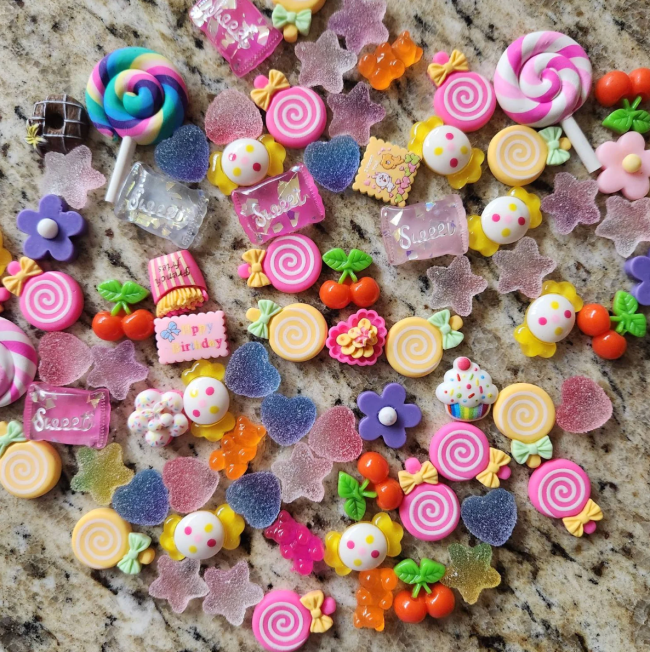 A pile of resin candy beads and charms on a granite background
