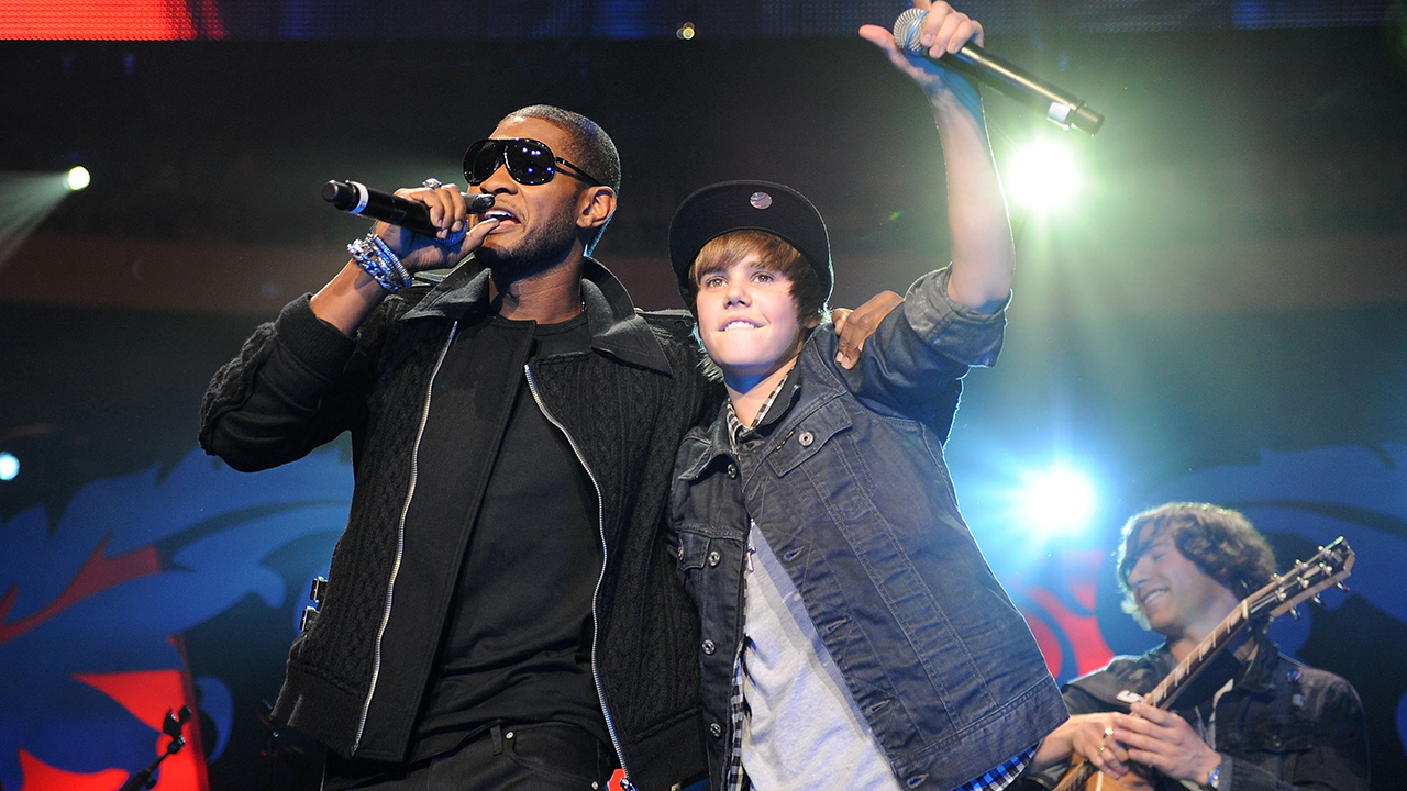 Justin Bieber Super Bowl. Usher with sunglasses singing while Justin Bieber in a denim jacket raising his microphone
