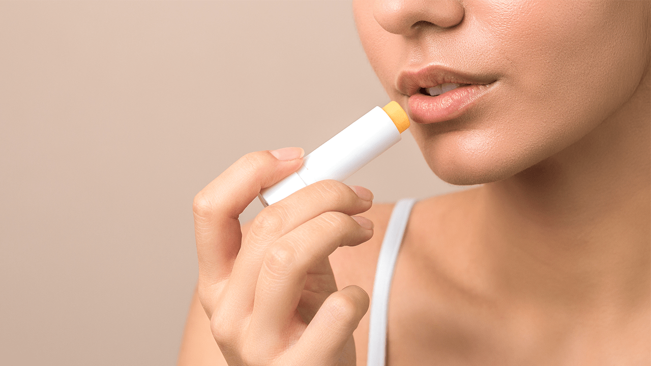 Woman applying lip balm to chapped lips