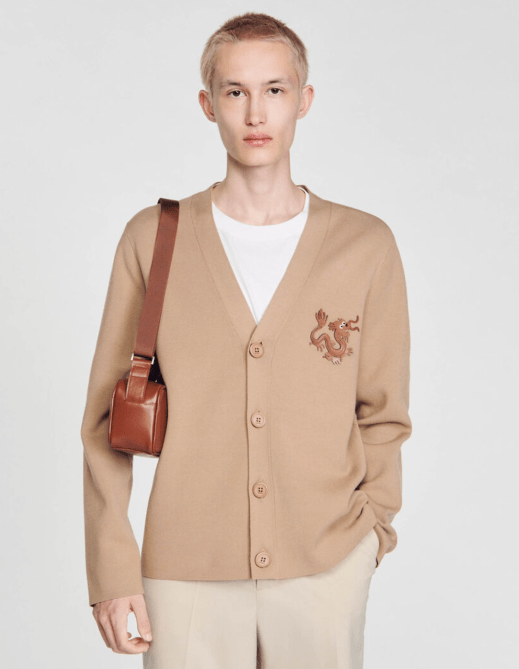 A model wearing a beige dragon-adorned cardigan from Sandro