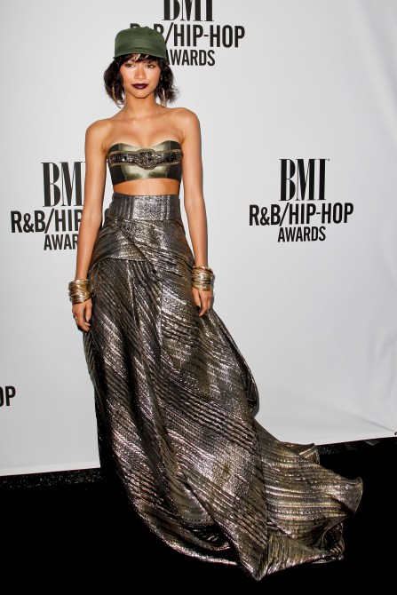 Zendaya in a two-piece metallic evening gown and olive green ball cap at the BMI red carpet
