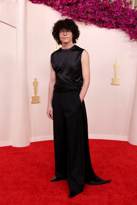Reece Feldman at the 2024 Oscars red carpet in a black silk tank and wide-leg black pants