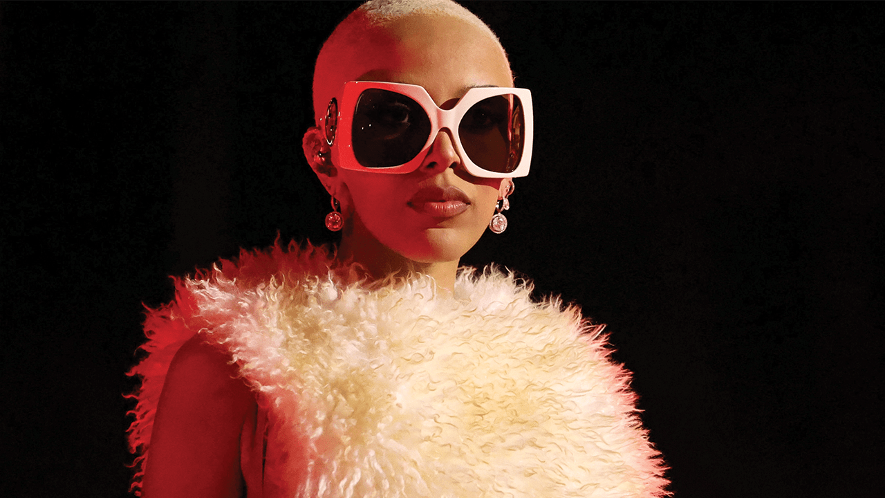 Doja Cat wearing a furry two-piece bikini and oversized white sunglasses.