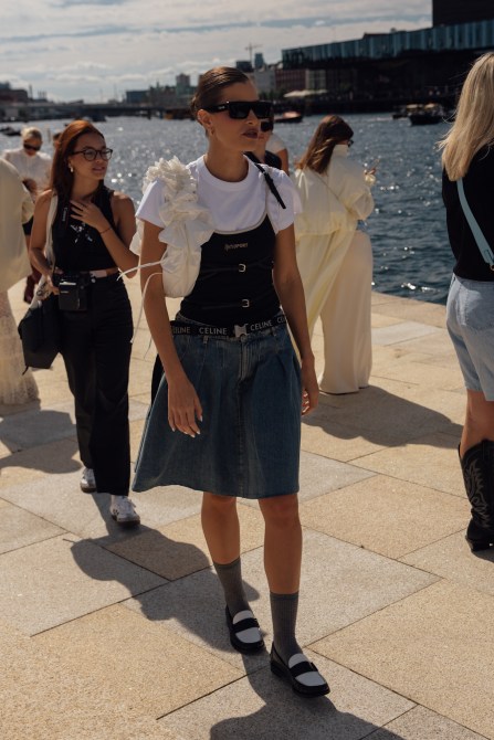 A fashion week guest wearing a tank top over a white t-shirt.