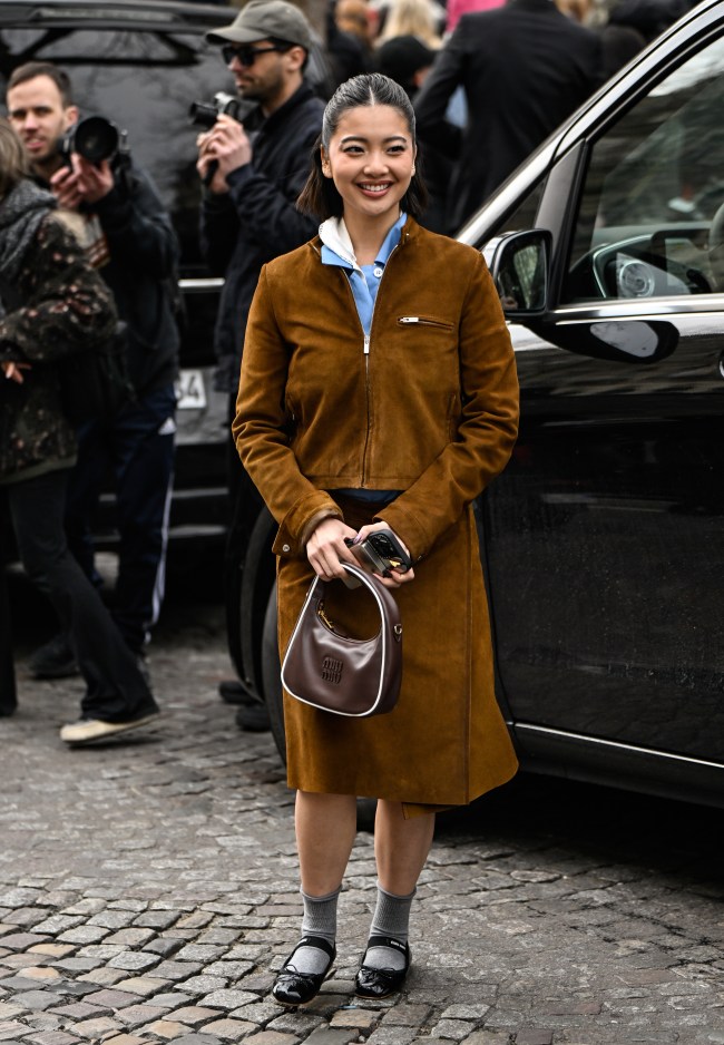 Stephanie Hui is seen wearing a brown Miu Miu jacket, brown Miu Miu skirt, brown and white Miu Miu bag and black shoes with gray socks outside the Miu Miu show during the Womenswear Fall/Winter 2025/2026 as part of Paris Fashion Week on March 11, 2025 in Paris, France.