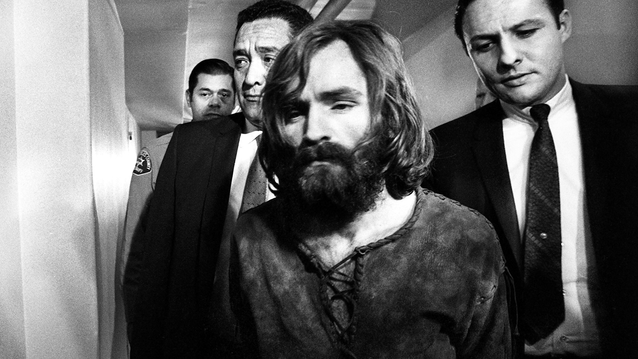 Charles Manson, accused leader of a hippie cult charged with the Tate-LaBianca murders, leaves court after deferring a plea on the murder charges.  The 35-year-old Manson was clad in a filthy fringed buckskin jacket and trousers and a full length beard when he appeared before Judge William B. Keene in the packed courtroom.