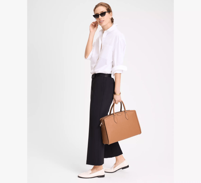A model carrying the Kate Spade Hudson Commuter Laptop Bag in light brown